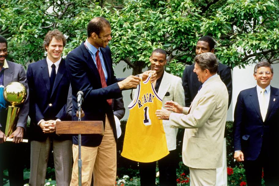 1985: Kareem guida la delegazione dei Lakers che fa visita al presidente Ronald Regan alla Casa Bianca. E gli consegna la maglia gialloviola col numero 1